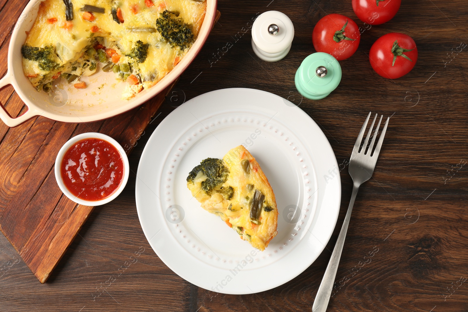 Photo of Tasty vegetable casserole served with sauce and spices on wooden table, flat lay