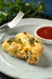 Photo of Piece of tasty vegetable casserole and sauce on blue table, closeup