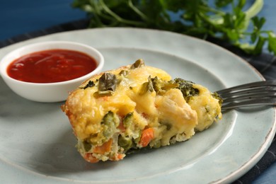 Photo of Piece of tasty vegetable casserole and sauce on blue table, closeup