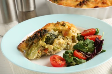 Photo of Tasty vegetable casserole and salad on white wooden table, closeup