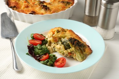 Photo of Tasty vegetable casserole and salad on white wooden table, closeup