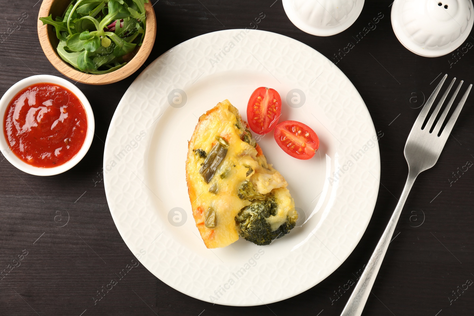 Photo of Tasty vegetable casserole served on black wooden table, flat lay