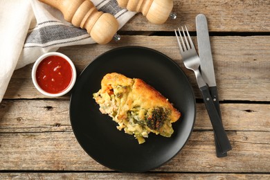 Photo of Tasty vegetable casserole, sauce, cutlery and shakers on wooden table, flat lay