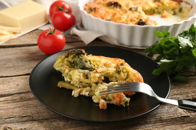 Photo of Tasty vegetable casserole and fork on wooden table, closeup