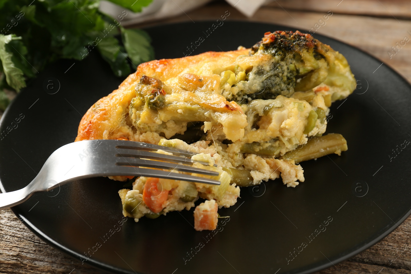 Photo of Tasty vegetable casserole and fork on wooden table, closeup