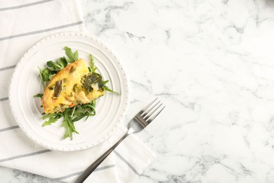 Photo of Tasty vegetable casserole, arugula and fork on white marble table, top view. Space for text