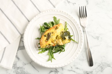 Photo of Tasty vegetable casserole, arugula and fork on white marble table, top view