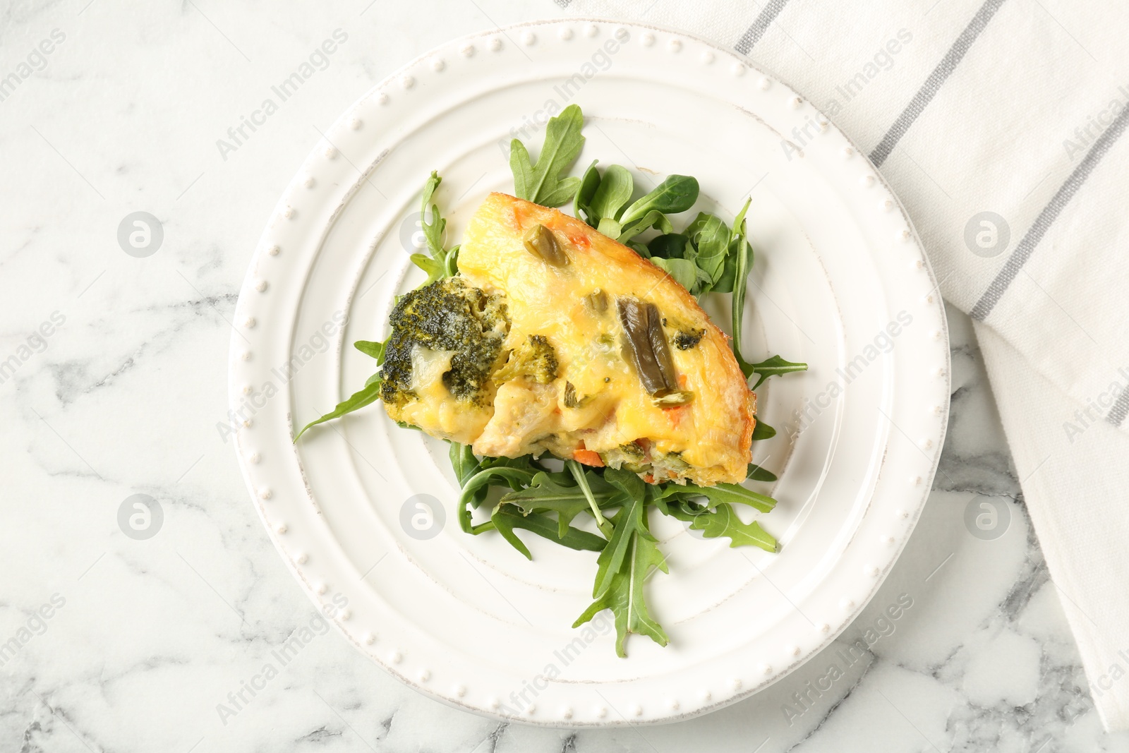 Photo of Tasty vegetable casserole and arugula on white marble table, top view