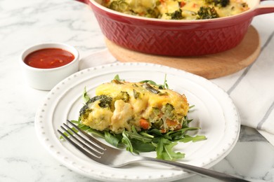 Photo of Tasty vegetable casserole, arugula and fork on white marble table, closeup