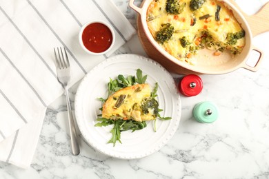 Photo of Tasty vegetable casserole, arugula, shakers, sauce and fork on white marble table, flat lay