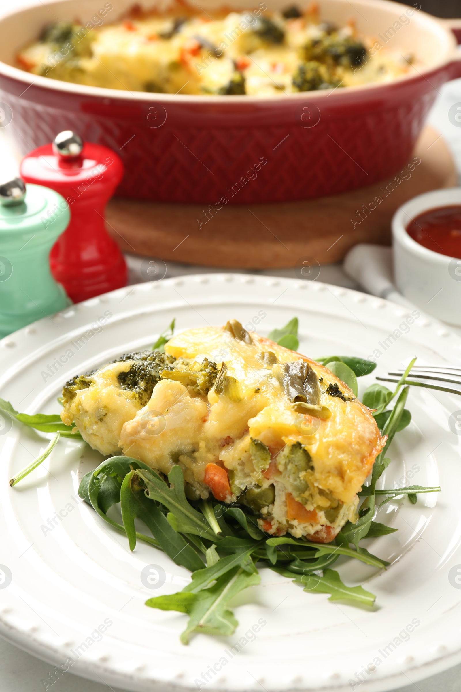 Photo of Tasty vegetable casserole and arugula on white table, closeup