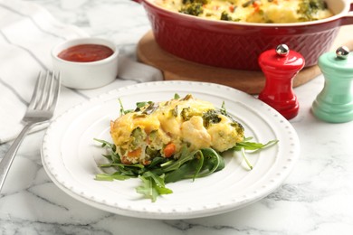 Photo of Tasty vegetable casserole and arugula on white marble table, closeup