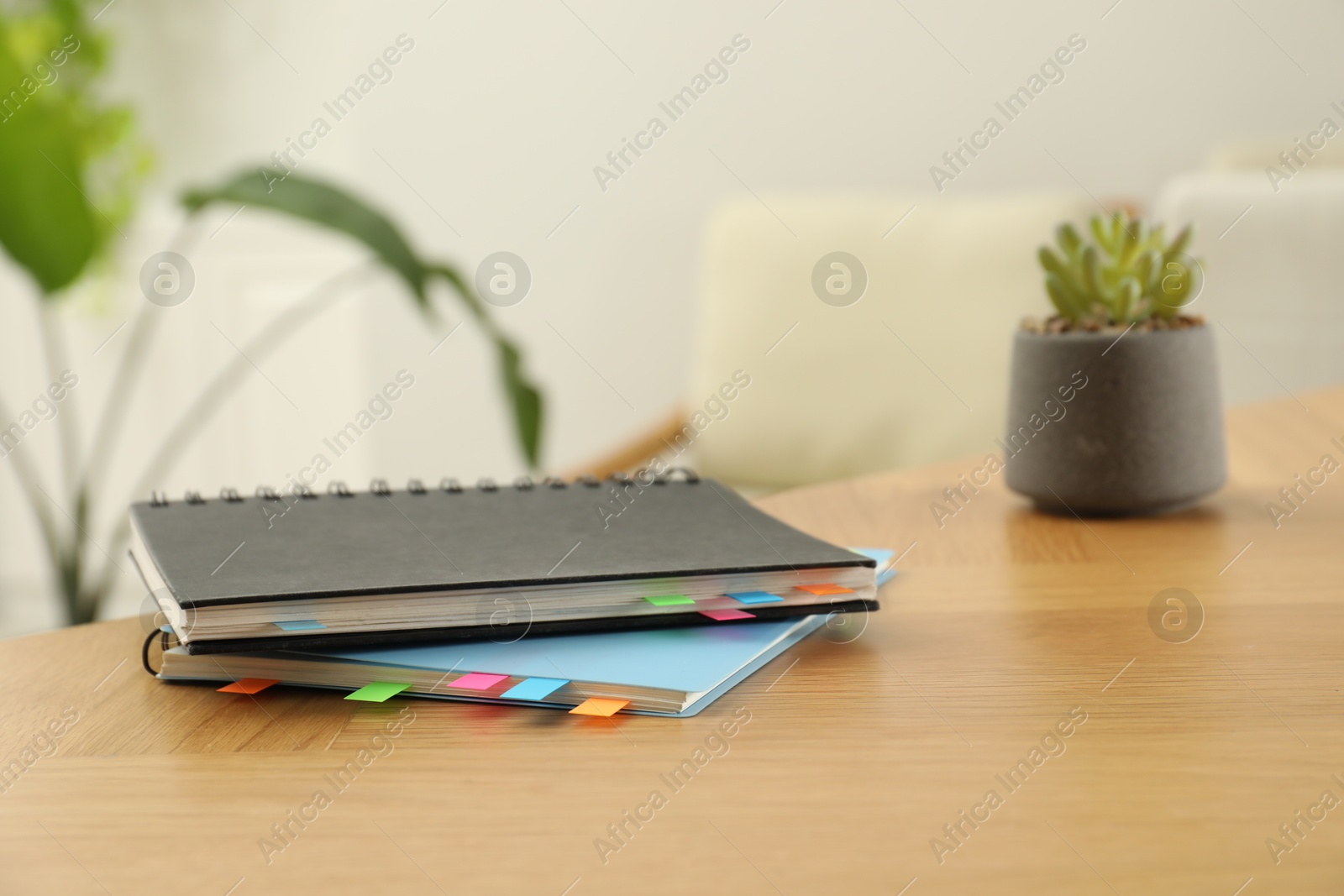 Photo of Notebooks with colorful bookmarks on wooden table. Space for text