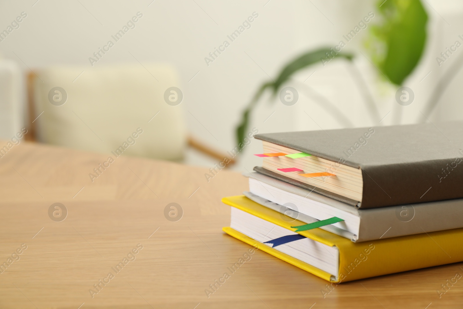 Photo of Stack of books with colorful bookmarks on wooden table, closeup. Space for text