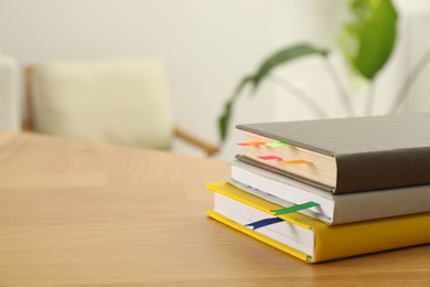 Photo of Stack of books with colorful bookmarks on wooden table, closeup. Space for text