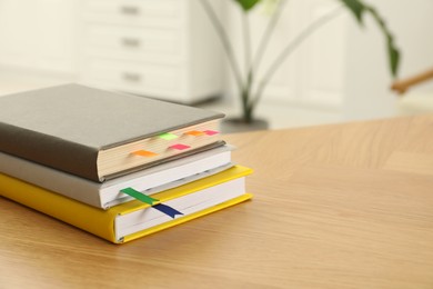 Photo of Stack of books with colorful bookmarks on wooden table, closeup. Space for text