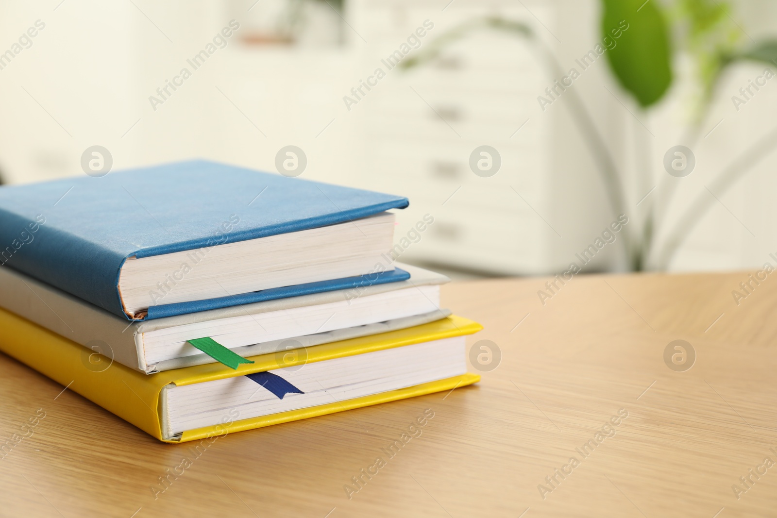 Photo of Stack of books with colorful bookmarks on wooden table, closeup. Space for text