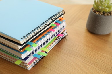 Photo of Stack of notebooks with colorful bookmarks on wooden table, closeup