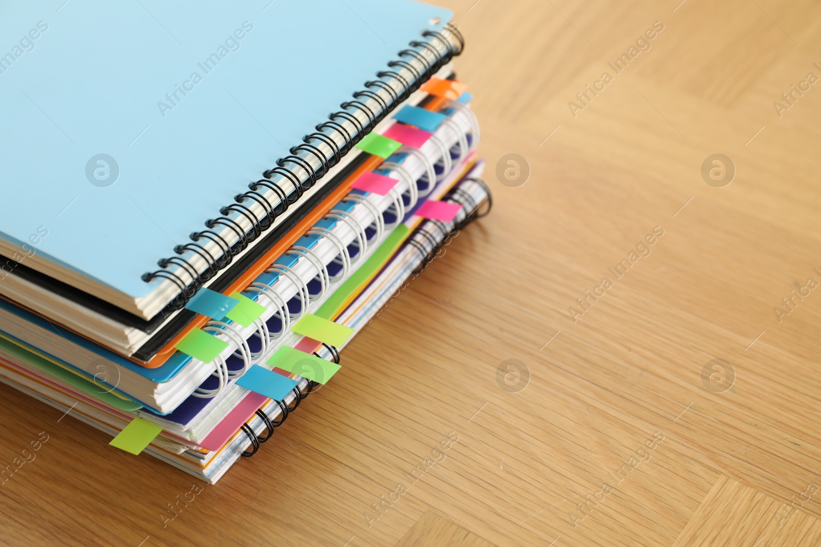 Photo of Stack of notebooks with colorful bookmarks on wooden table, closeup. Space for text