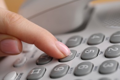 Photo of Woman dialing number on landline telephone, closeup