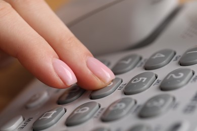 Photo of Woman dialing number on landline telephone, closeup