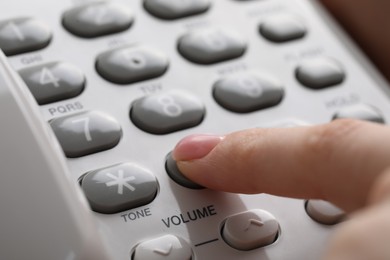 Photo of Woman dialing number on landline telephone, closeup