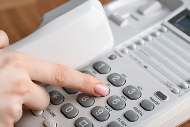 Photo of Woman dialing number on telephone at table, closeup