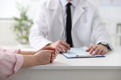 Photo of Woman having appointment with doctor in hospital, closeup