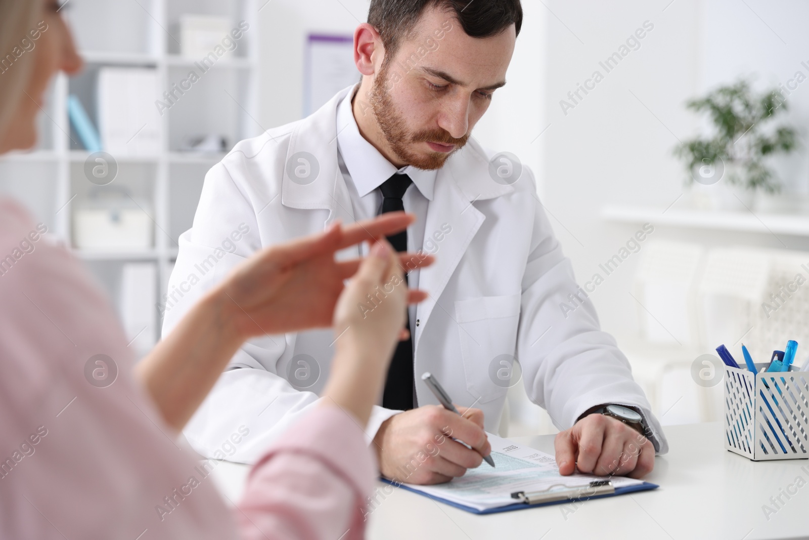 Photo of Doctor and his patient at desk in hospital