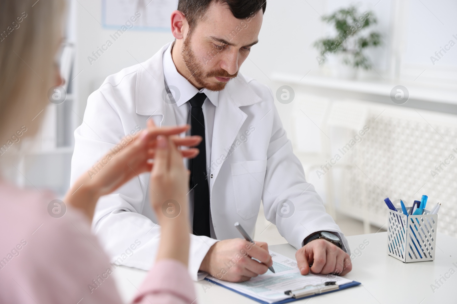 Photo of Doctor and his patient at desk in hospital