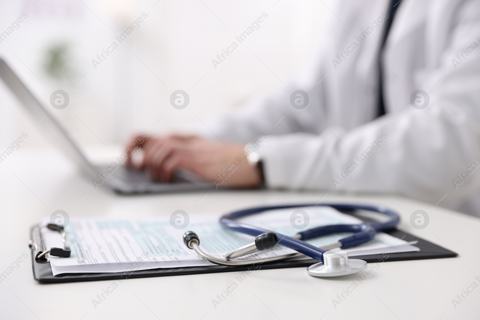 Photo of Professional doctor working on laptop at desk in hospital, closeup