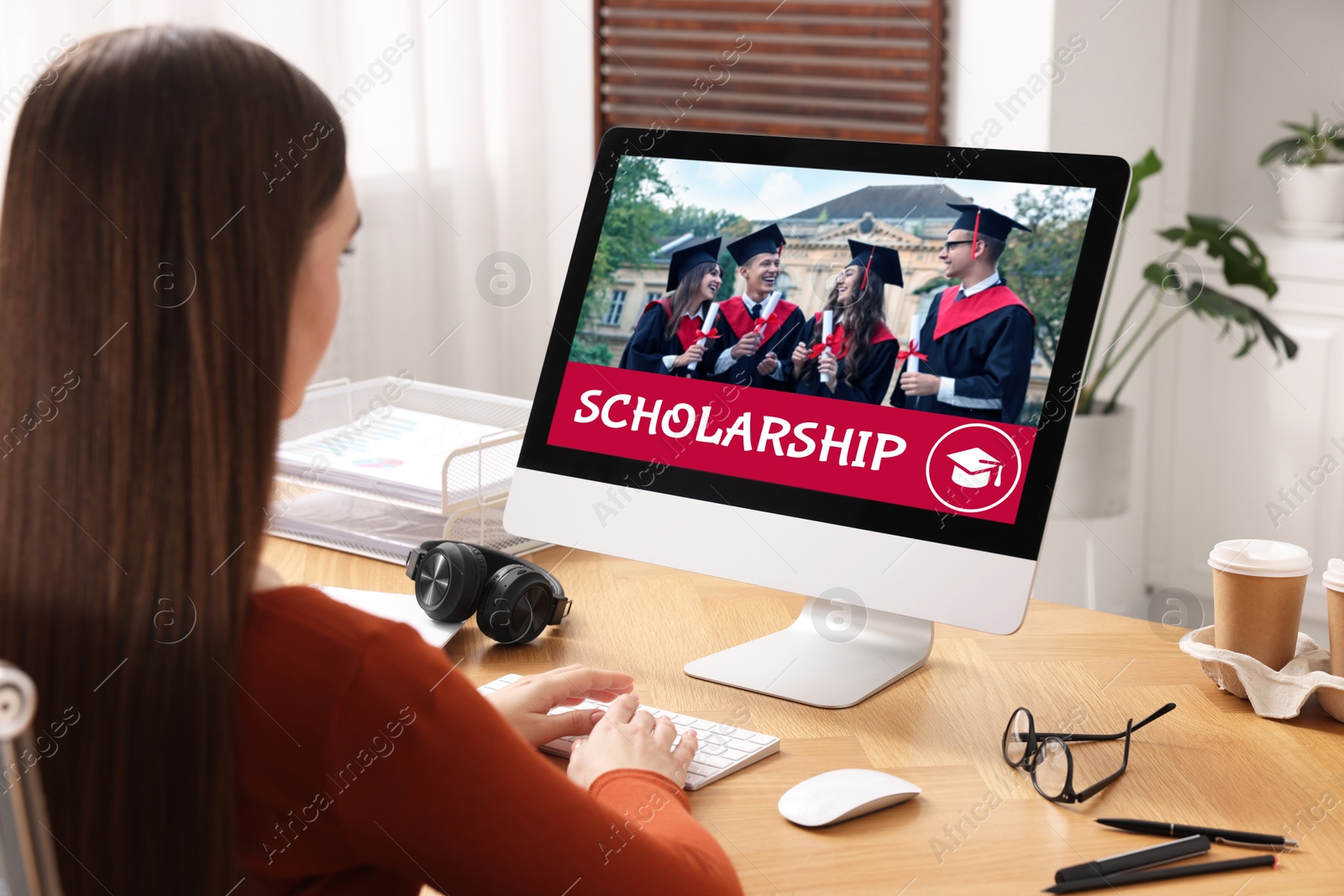 Image of Student searching for scholarships using computer at home. Open website on display