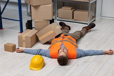 Photo of Accident at work. Unconscious man lying on floor in warehouse