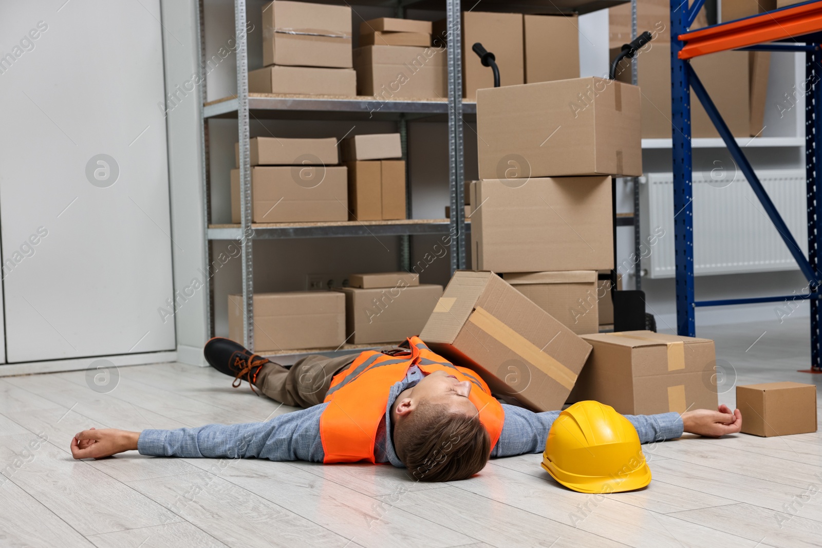 Photo of Accident at work. Unconscious man lying on floor in warehouse