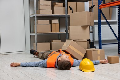 Photo of Accident at work. Unconscious man lying on floor in warehouse