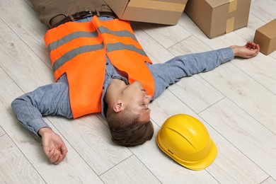 Photo of Accident at work. Unconscious man lying on floor in warehouse