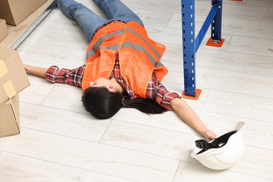 Photo of Accident at work. Unconscious woman lying on floor in warehouse