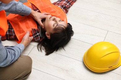 Photo of Accident at work. Man checking pulse of his unconscious colleague in warehouse, closeup