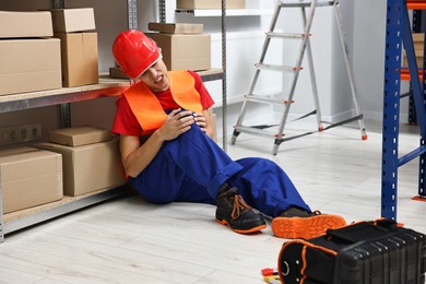 Photo of Accident at work. Injured man with toolkit on floor in warehouse