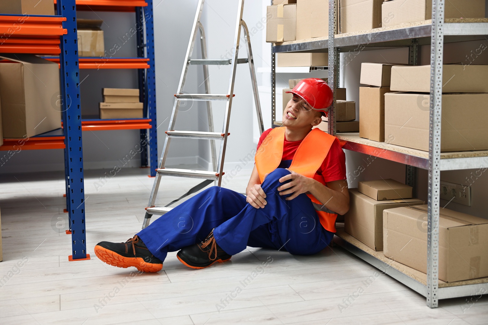 Photo of Accident at work. Injured man on floor in warehouse