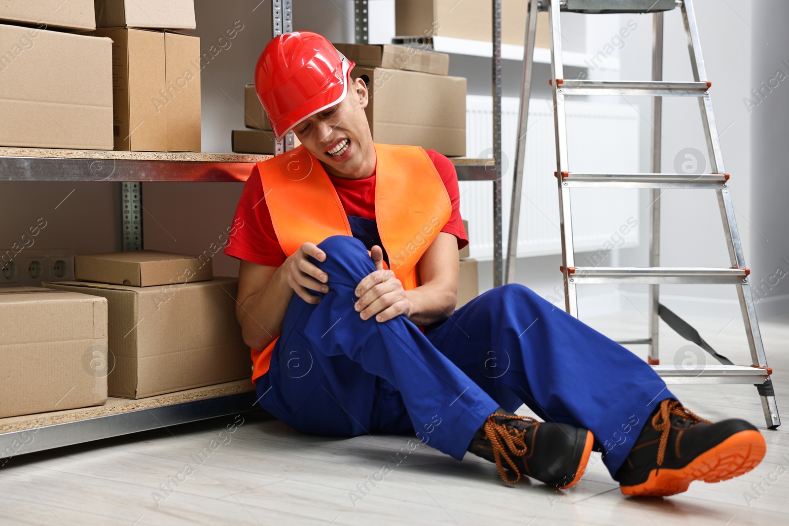 Photo of Accident at work. Injured man on floor in warehouse