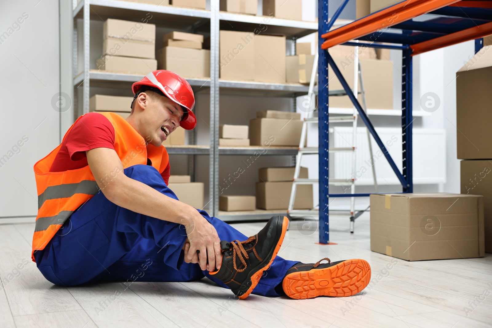 Photo of Accident at work. Injured man on floor in warehouse