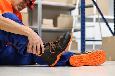 Photo of Accident at work. Injured man on floor in warehouse, closeup