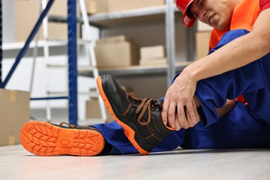 Photo of Accident at work. Injured man on floor in warehouse, closeup