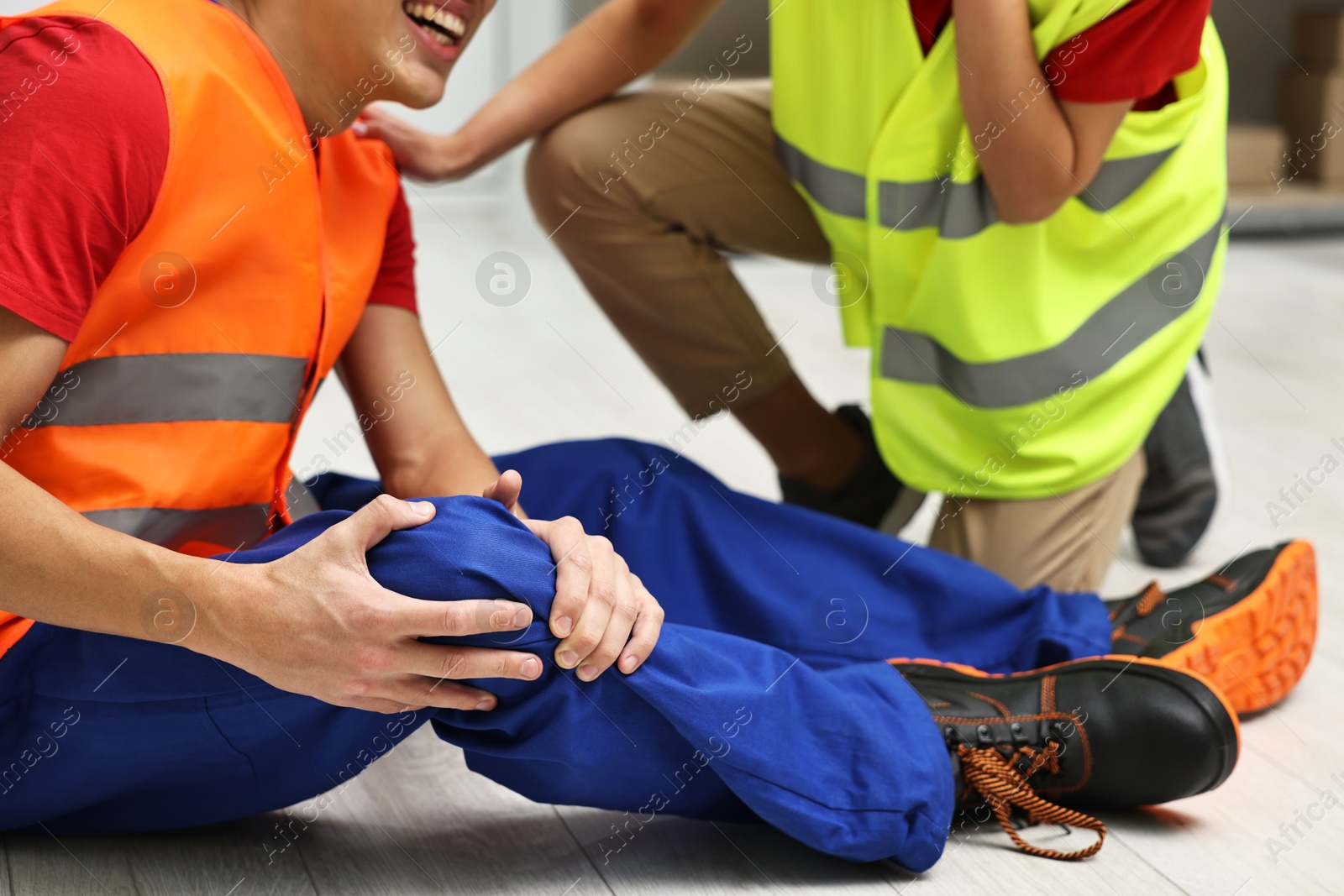 Photo of Accident at work. Woman helping her injured colleague in warehouse, closeup