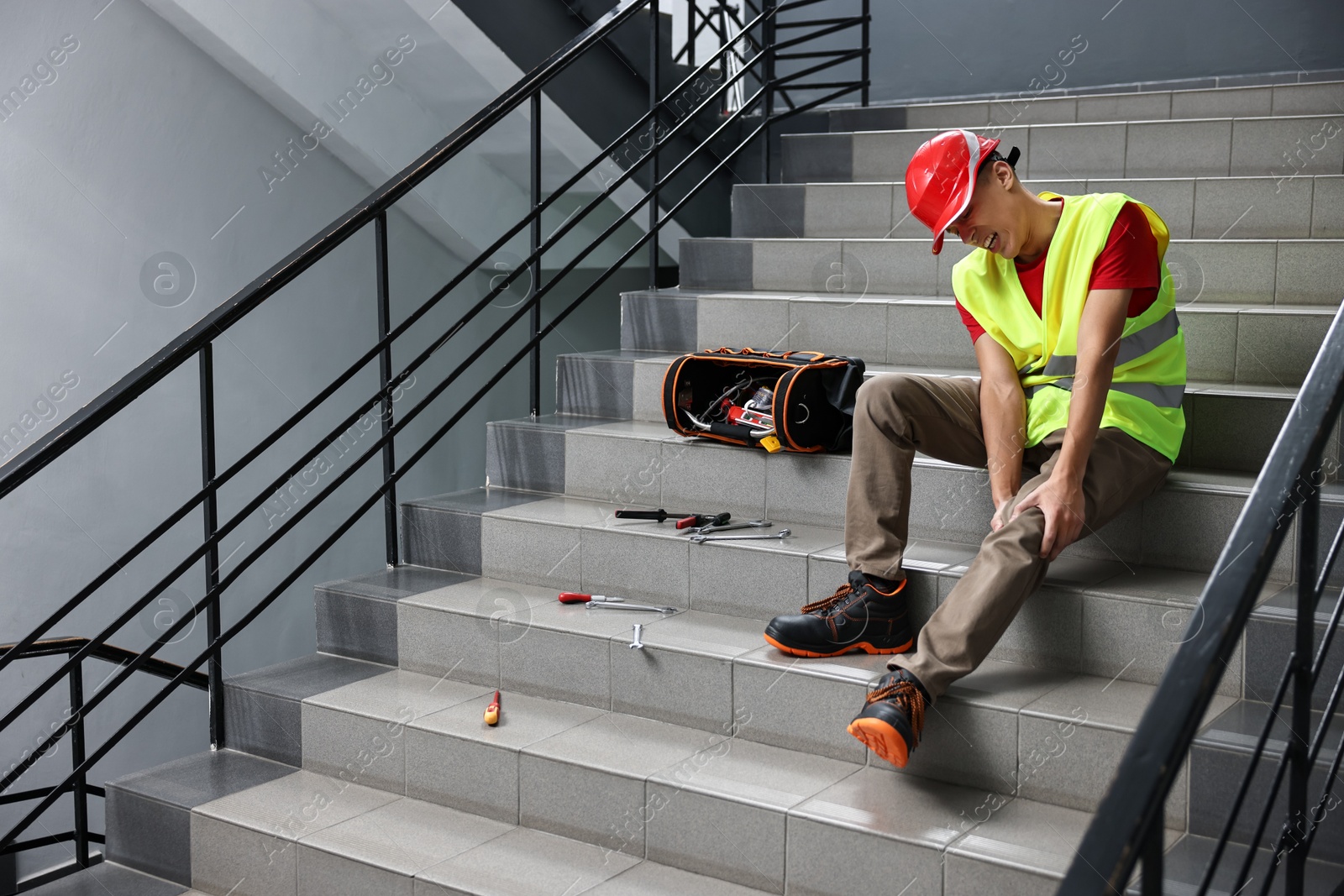 Photo of Accident at work. Injured man on stairs indoors. Space for text