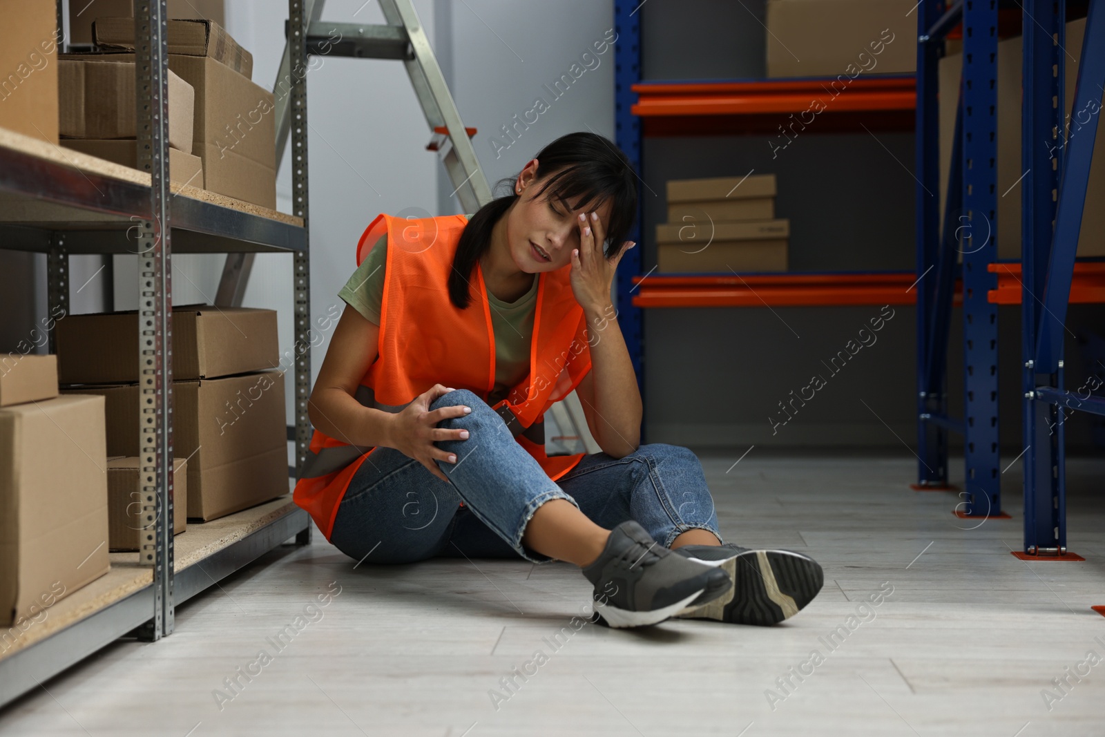 Photo of Accident at work. Injured woman on floor in warehouse