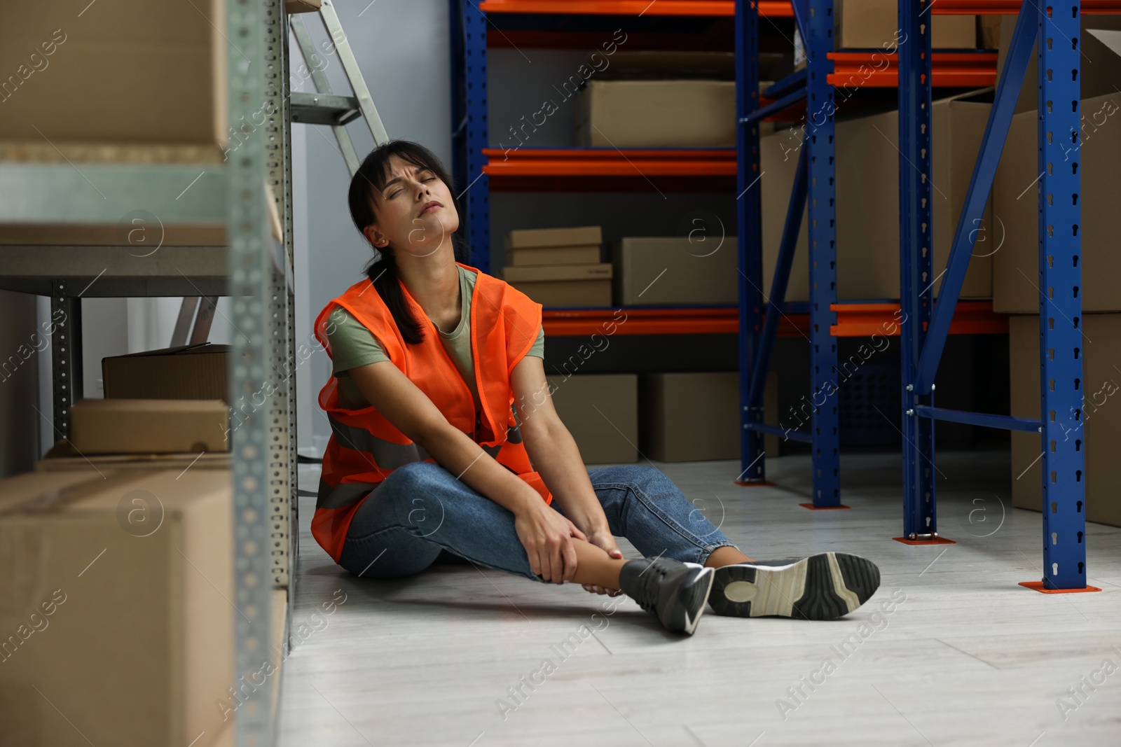 Photo of Accident at work. Injured woman on floor in warehouse