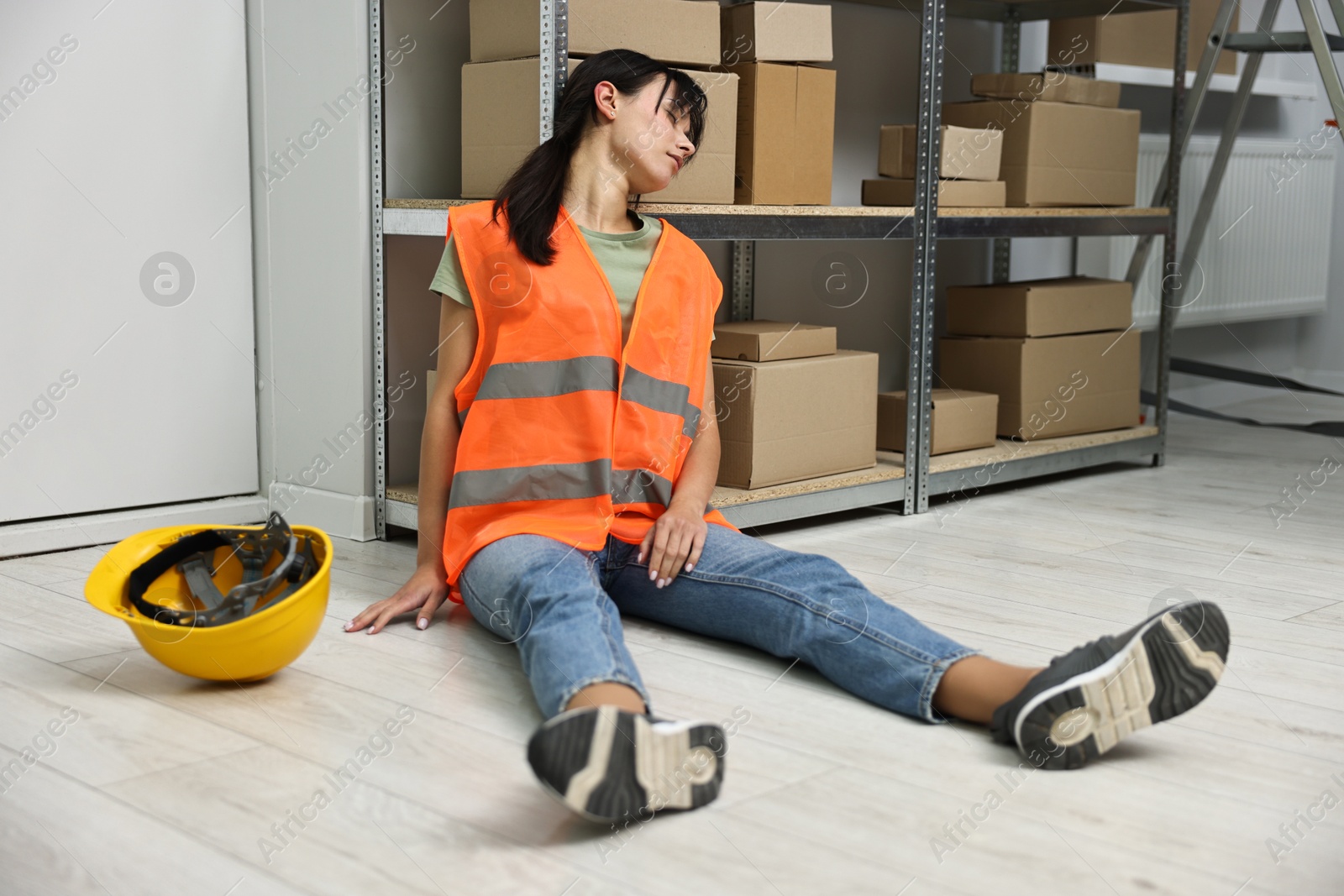 Photo of Accident at work. Unconscious woman on floor in warehouse