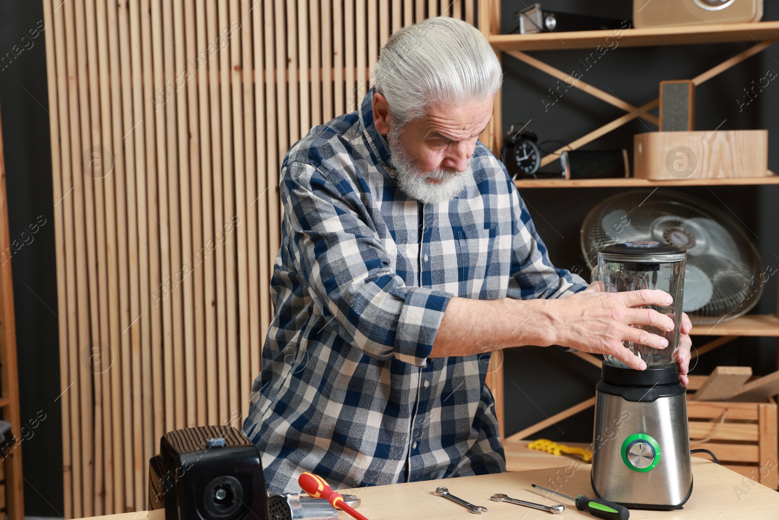 Photo of Relaxing hobby. Senior man repairing blender in workshop